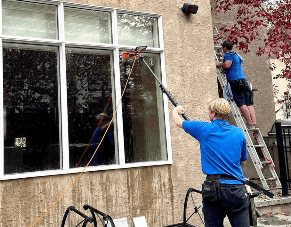 Capt. Clean employees washing the outside windows of a residential home.